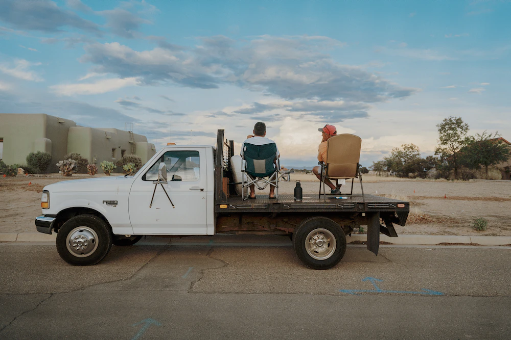 men sitting on the flat bed of a utility truck